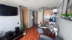 a living room with a table and chairs and a kitchen at Departamentos Alpro Cavancha in Iquique