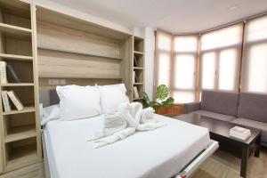 Un dormitorio con una gran cama blanca y un sofá. en Cuencaloft Hurtado de Mendoza, en Cuenca