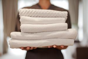 a woman holding a stack of white towels at Detroit Marriott Livonia in Livonia