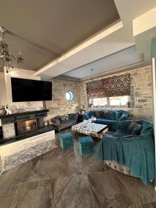 una sala de estar con sofás azules y una pared de piedra. en Porti villas, en Áno Moúlia
