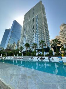 a large swimming pool with chairs and buildings at Beach Please in Dubai