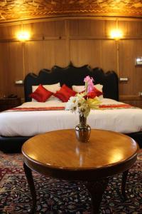 a bedroom with a bed and a table with flowers on it at New York Houseboat in Srinagar