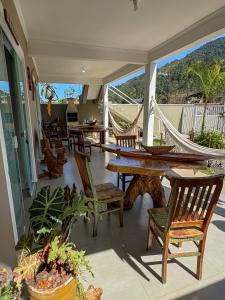 a porch with chairs and tables and a hammock at Chalé do Gaúcho in Ubatuba