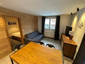 a living room with a table and a blue couch at 3 pièces, 2 chambres, balcon et parking, pour 6 personnes - FR-1-263-89 in Valloire