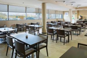 a dining room with tables and chairs and windows at Holiday Inn Express Campo de Gibraltar-Barrios by IHG in Los Barrios