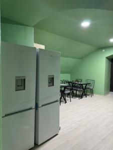 two white refrigerators in an empty room with tables at Equator Hostel in Chişinău