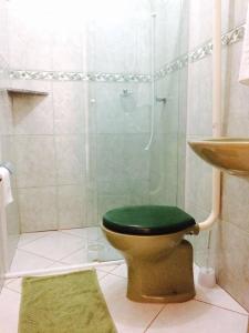 a bathroom with a shower with a toilet with a green seat at Moradas da Bibi in Guarda do Embaú