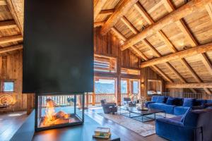 マニグードにあるLodge Les Murailles Luxury Unique Alpin Chalet Manigod La Clusazのログハウス内のリビングルーム(暖炉付)