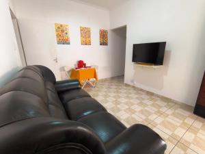 a living room with a leather couch and a television at Doce Recanto da re in Franca