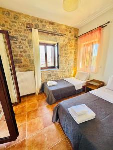 a room with two beds and a brick wall at Mani Spot Sunset View in Areopolis +24 photos