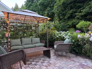 a patio with a couch and chairs under a gazebo at Five Gables B&B in Qualicum Beach
