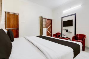 a bedroom with a bed and two red chairs at Hotel O Ayushman in Jabalpur +22 photos