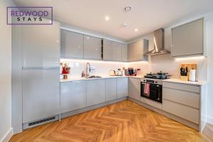 a kitchen with white cabinets and a wooden floor at Brand New Premium Serviced Apartments, Free Parking, High-Speed WiFi By Redwood Stays in Cove