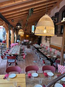 a restaurant with many tables and chairs and a chandelier at Les Chambres - Au Grès du marché in La Petite-Pierre