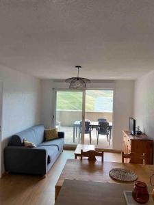 a living room with a blue couch and a table at Appartement T2 vue sur Pyrénées in Germ