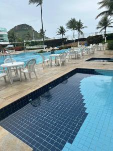 a swimming pool with a table and chairs and a table and a table at Maravilhoso flat 2 in Rio de Janeiro
