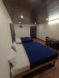a bedroom with two beds in a room with a table at Mountain Vista Vagamon in Vagamon