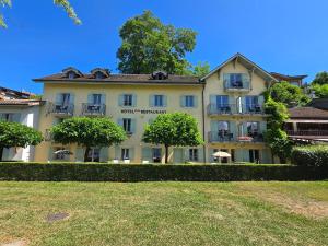 Hôtel La Riviera Victoria في إيفوار: مبنى أبيض كبير مع أشجار أمامه