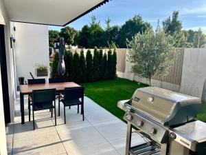 a backyard with a grill and a table and chairs at Olea Prien - Chiemsee Apartment in Prien am Chiemsee