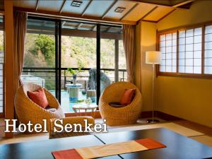 a living room with two chairs and a table and windows at Senkei in Hakone