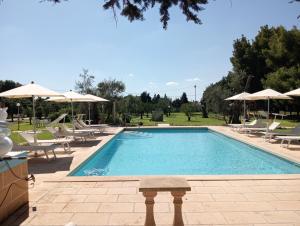 a swimming pool with lounge chairs and umbrellas at Agriturismo Santa Chiara in Alezio