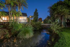 a garden with a pond in front of a house at Best Western Braeside Rotorua in Rotorua