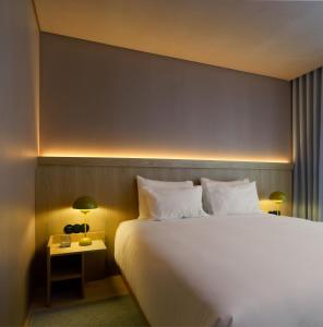 Un dormitorio con una gran cama blanca y una mesita de noche. en Akeah Porto Centro, en Oporto