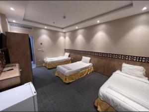a hotel room with two beds and a television at فندق شركة وردة الوادي توصيل من والي الحرم 24 مجاني in An Naqāʼ