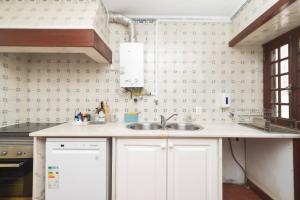 a kitchen with white cabinets and a sink at WOT Lodge Soul in Ericeira