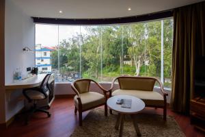 Una sala de estar con una mesa y sillas y una gran ventana. en Emerald Hotel, en Āīzawl