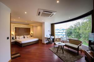 Una habitación de hotel con una cama, un sofá y un televisor. en Emerald Hotel, en Āīzawl
