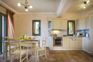 a kitchen with a table and chairs and a kitchen with white cabinets at Villa Leanda by Villa Plus in Lourdhata