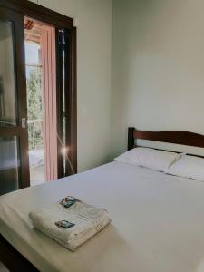 a bedroom with a white bed with a towel on it at Hotel Girassol in Imbé +25 photos