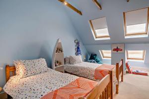 2 Betten in einem Zimmer mit blauen Wänden und Fenstern in der Unterkunft The Ferry Cottage in Walton