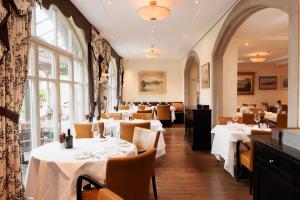 a restaurant with white tables and chairs and windows at Boutiquehotel Sonne Küsnacht - Zürich in Küsnacht