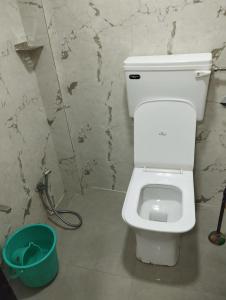 a bathroom with a white toilet and a bucket at Sun Shine AC Dormitory in Mumbai