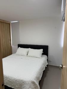 a white bed with two pillows on top of it at Apartamento moderno para rentar por Días - Nuevo in Barranquilla +13 photos