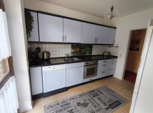 a kitchen with white cabinets and a sink and a rug at Feldzauber in Ladbergen