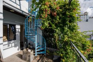a blue spiral staircase next to a tree with flowers at Aluna Residence Homestay in Danang