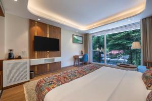 ein Hotelzimmer mit einem Bett und einem Flachbildfernseher in der Unterkunft Snow Valley Heights - An Elegant Air Conditioned Escape by Snow Valley Resorts in Manali