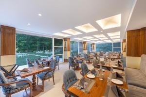 ein Restaurant mit Holztischen und -stühlen und großen Fenstern in der Unterkunft Snow Valley Heights - An Elegant Air Conditioned Escape by Snow Valley Resorts in Manali