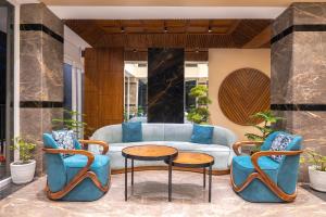 ein Wohnzimmer mit Couch und Stühlen in der Unterkunft Snow Valley Heights - An Elegant Air Conditioned Escape by Snow Valley Resorts in Manali