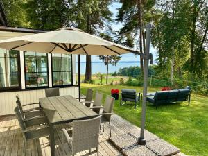 a table and chairs with an umbrella on a deck at The Manor Wing, Lake View & Outdoor Spa in Vreta Kloster