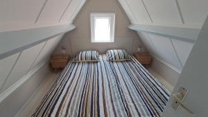 a attic room with two beds and a window at Camino in Vrouwenpolder