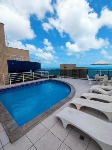 a swimming pool on top of a building with tables and chairs at Flat Beira Mar Fortaleza in Fortaleza