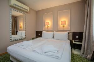 a bedroom with a large white bed and a mirror at Hotel Attaché l contactless check-in in Vienna