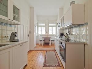 a kitchen with white cabinets and a wooden floor at BG Living & Hosting - Stilvolles Jugendstilhaus am Marktplatz - Top-Lage im Zentrum in Traben-Trarbach