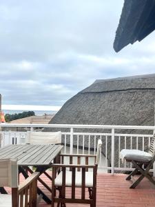 a patio with a table and chairs on a balcony at Lala Panzi - Grotto Beach, Voëlklip in Hermanus
