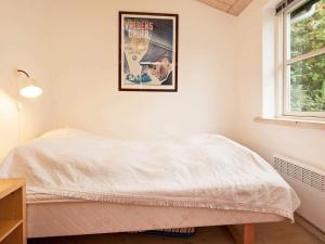a bed in a room with a poster on the wall at 4 star holiday home in Dronningmølle in Dronningmølle