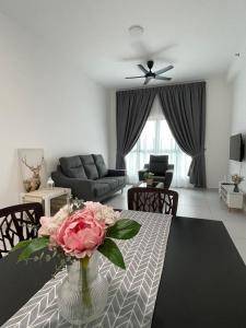 Una sala de estar con una mesa con un jarrón de flores. en NEW Batu Kawan 2 Bedrooms Suite near IKEA-Columbia Asia Hospital-BKIP-UOW Kdu, en Simpang Ampat